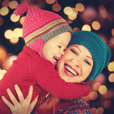 Mother and little girl hugging as they look at Christmas lights
